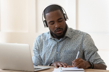 man at laptop taking notes